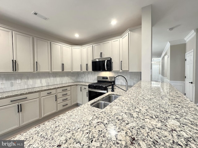 kitchen with appliances with stainless steel finishes, sink, backsplash, light stone counters, and crown molding