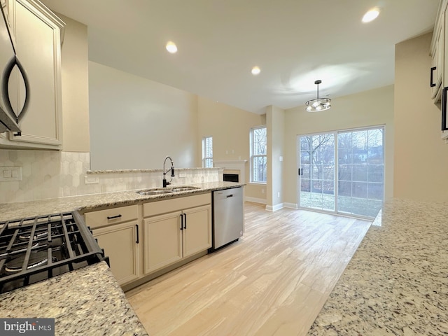 kitchen with sink, dishwasher, hanging light fixtures, tasteful backsplash, and light stone countertops