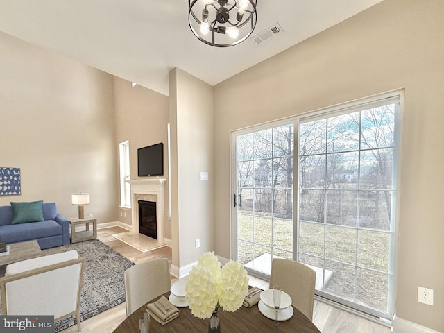 dining area with a healthy amount of sunlight, a fireplace, and light wood-type flooring