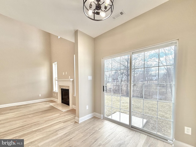 unfurnished living room featuring a high end fireplace, plenty of natural light, and light hardwood / wood-style floors