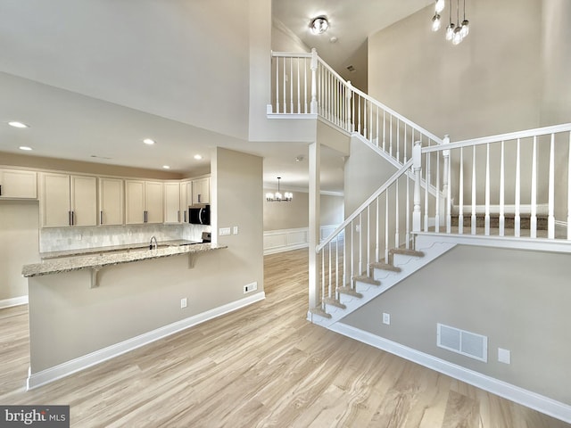 interior space featuring a towering ceiling, hardwood / wood-style floors, and an inviting chandelier