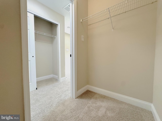 walk in closet with light colored carpet