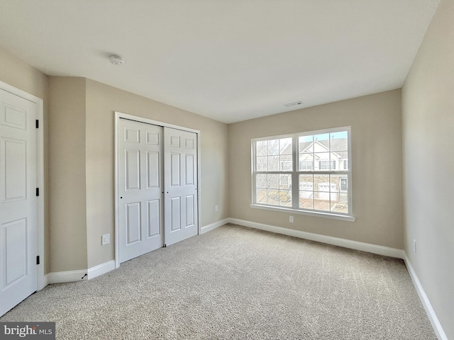 unfurnished bedroom with light colored carpet and a closet