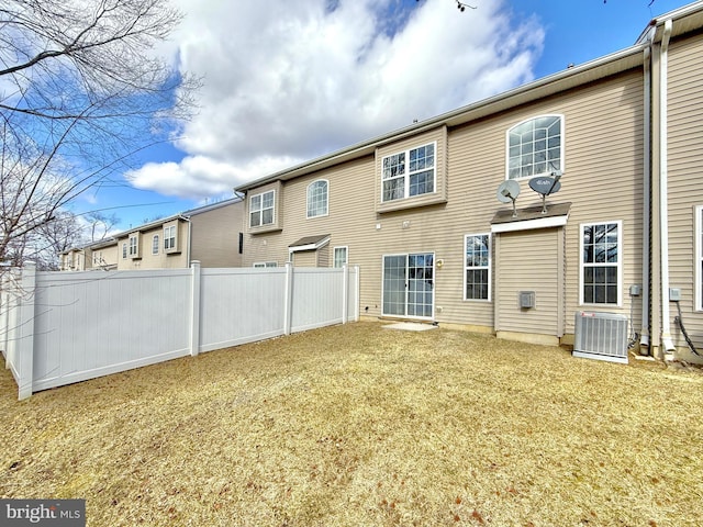 rear view of house featuring a lawn and central air condition unit