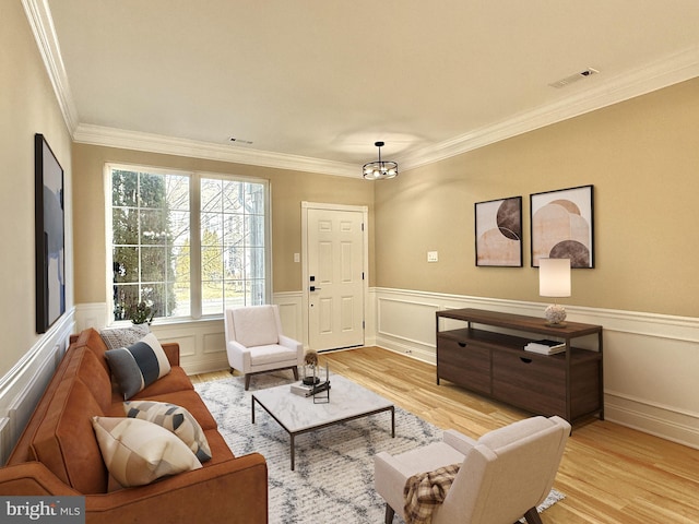 living area with light hardwood / wood-style flooring and ornamental molding