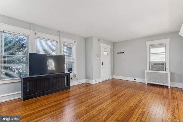 unfurnished living room with baseboards, hardwood / wood-style floors, and radiator heating unit