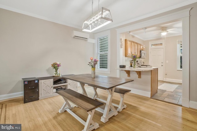 dining area with ornamental molding, ceiling fan, a wall unit AC, and light hardwood / wood-style flooring