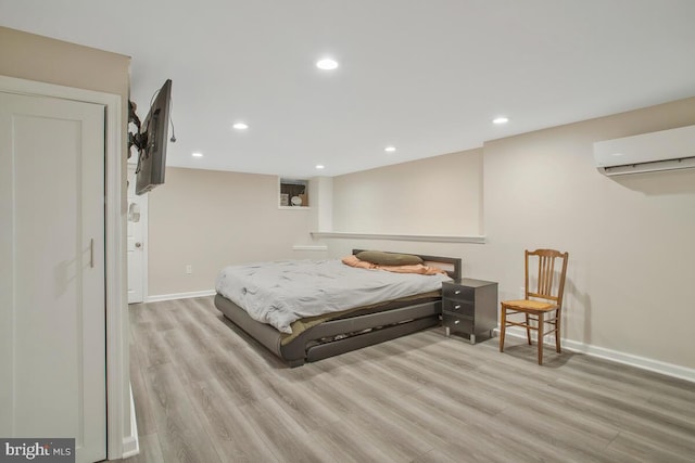 bedroom featuring a wall mounted air conditioner and light hardwood / wood-style flooring