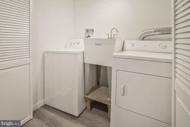 washroom with washing machine and dryer and light hardwood / wood-style flooring