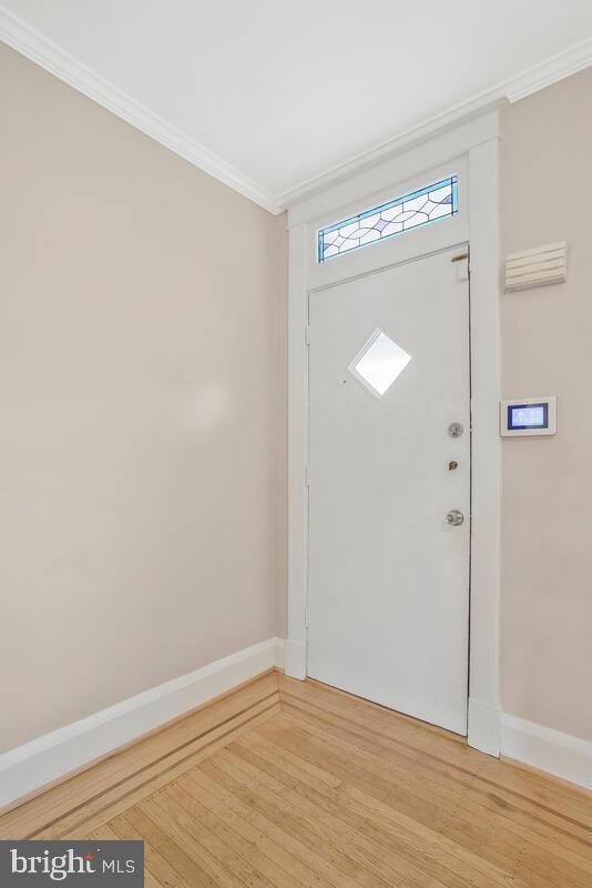 entryway with hardwood / wood-style flooring and crown molding