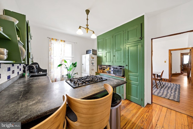 kitchen with stainless steel gas cooktop, light hardwood / wood-style flooring, kitchen peninsula, green cabinets, and white fridge