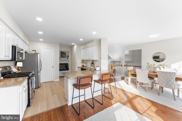 kitchen with kitchen peninsula, appliances with stainless steel finishes, white cabinets, and decorative backsplash