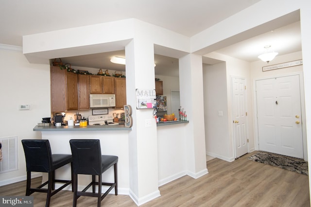 kitchen with a breakfast bar, range, kitchen peninsula, and light hardwood / wood-style floors