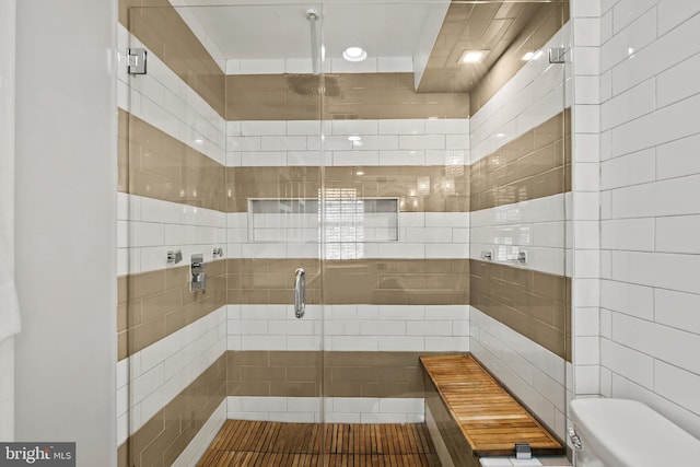 bathroom with tile walls, toilet, and walk in shower