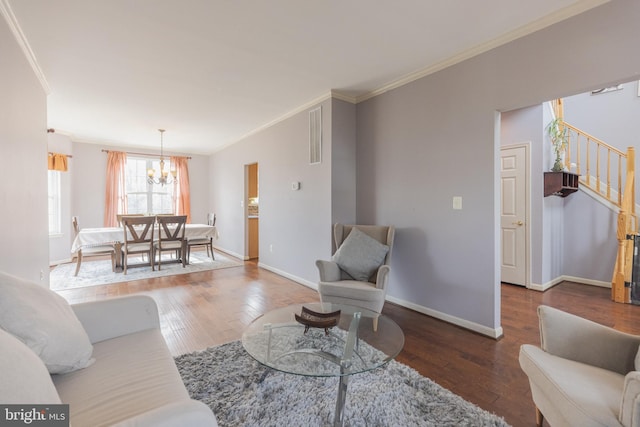 living room featuring an inviting chandelier, ornamental molding, and hardwood / wood-style floors