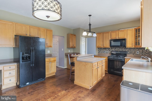 kitchen featuring dark wood-type flooring, sink, decorative light fixtures, a center island, and black appliances