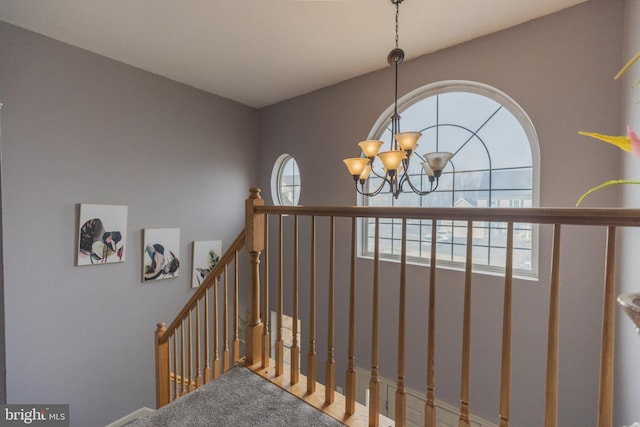 stairs featuring a healthy amount of sunlight and a chandelier