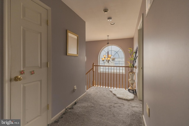 hallway with carpet flooring and a chandelier