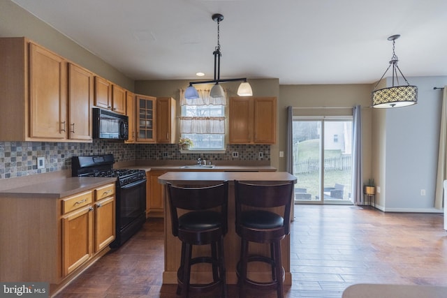 kitchen with pendant lighting, a breakfast bar area, a center island, tasteful backsplash, and black appliances