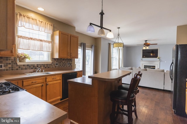 kitchen with a center island, pendant lighting, backsplash, and black appliances