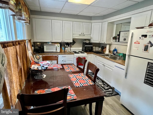 kitchen featuring sink, white appliances, a paneled ceiling, white cabinetry, and light wood-type flooring