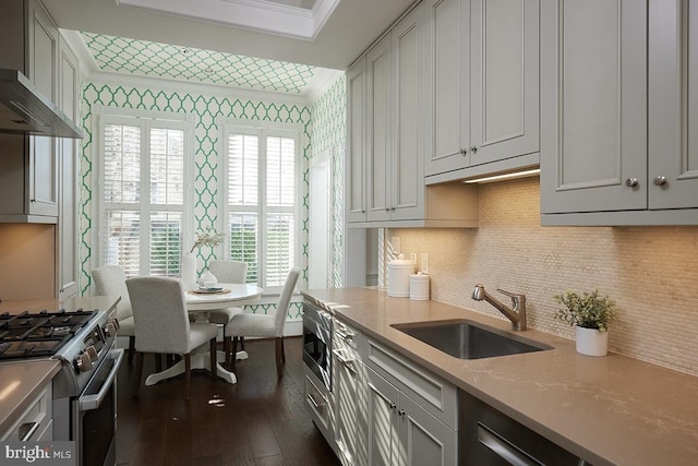 kitchen with sink, wall chimney range hood, appliances with stainless steel finishes, backsplash, and dark hardwood / wood-style flooring