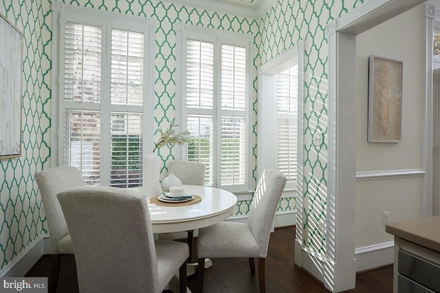 dining space featuring wallpapered walls, dark wood-style floors, and baseboards