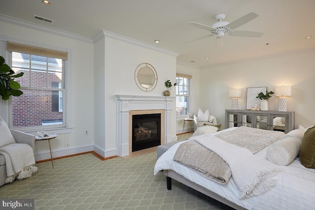 bedroom featuring baseboards, visible vents, crown molding, and a glass covered fireplace