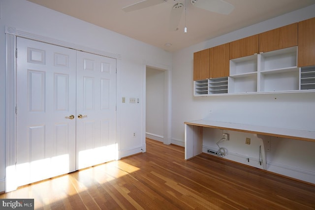 kitchen with brown cabinetry, a ceiling fan, light wood-type flooring, open shelves, and built in desk