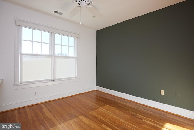 unfurnished room with visible vents, ceiling fan, baseboards, and wood finished floors