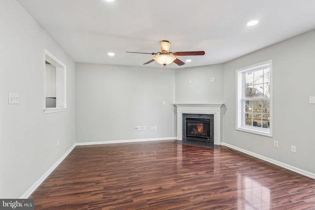 unfurnished living room featuring dark wood-type flooring and ceiling fan