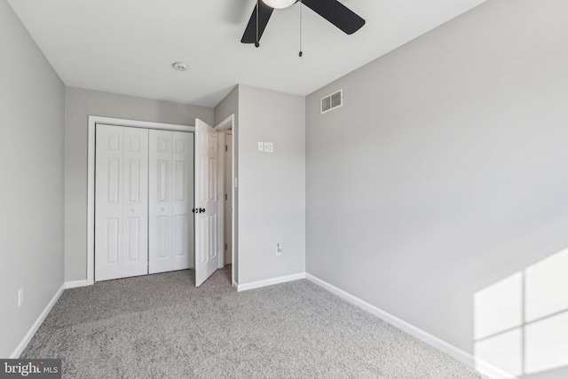 unfurnished bedroom featuring light colored carpet, ceiling fan, and a closet