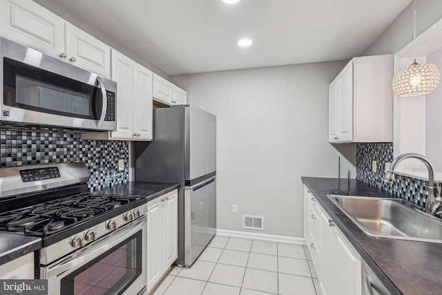 kitchen with sink, light tile patterned floors, appliances with stainless steel finishes, hanging light fixtures, and white cabinets