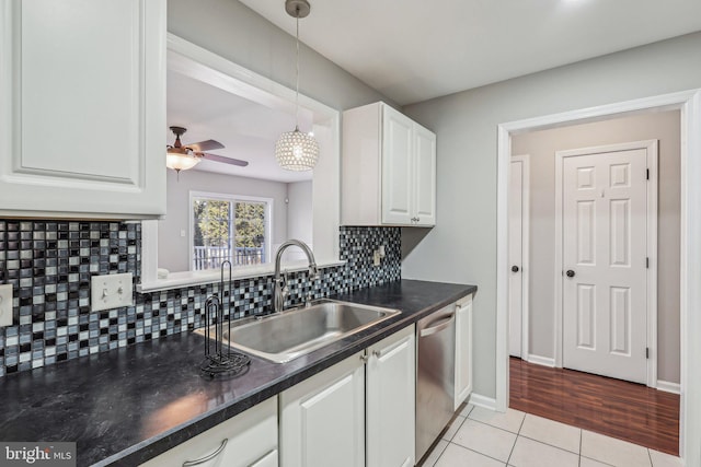 kitchen with sink, light tile patterned floors, dishwasher, white cabinetry, and decorative light fixtures