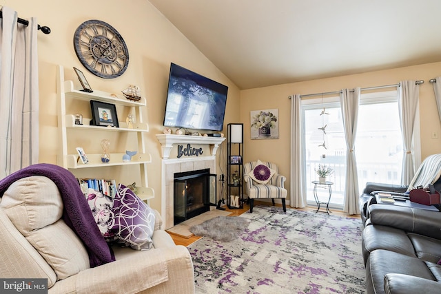 living room with lofted ceiling, a tiled fireplace, and light hardwood / wood-style floors