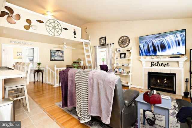 living room with ceiling fan, a fireplace, light hardwood / wood-style floors, and vaulted ceiling