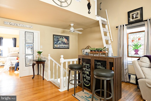 bar with hardwood / wood-style floors and ceiling fan