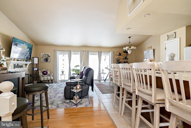 dining space featuring lofted ceiling, light wood-type flooring, and an inviting chandelier