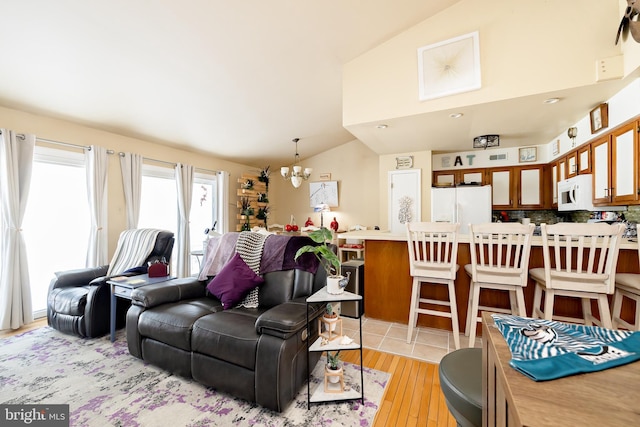 living room featuring vaulted ceiling, a notable chandelier, and light hardwood / wood-style floors