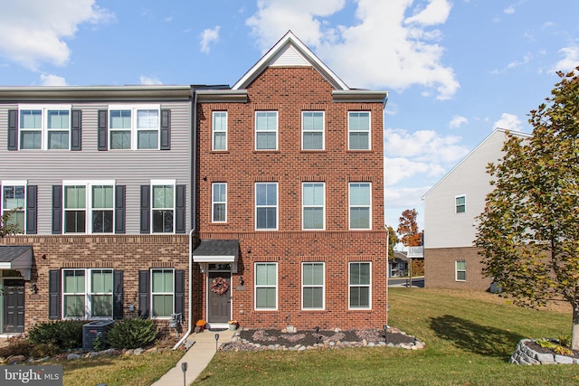 townhome / multi-family property with central air condition unit, a front lawn, and brick siding