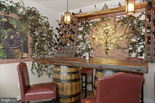 bar featuring decorative light fixtures and brick wall