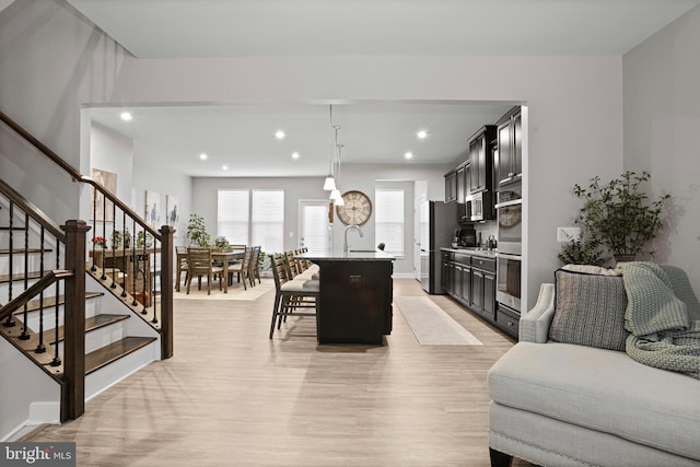 living room featuring light wood-type flooring, stairs, baseboards, and recessed lighting