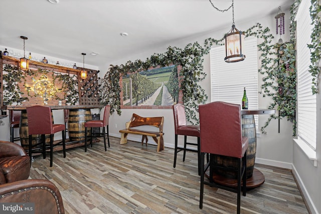 dining room featuring a bar, baseboards, and wood finished floors