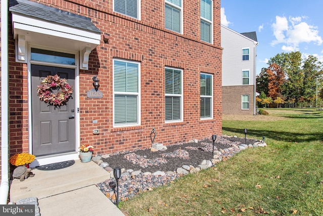 entrance to property with brick siding and a lawn