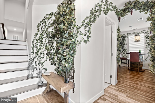 stairs with baseboards, visible vents, and wood finished floors