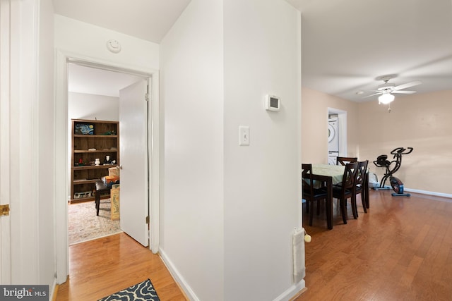 hall with stacked washer and dryer and wood-type flooring