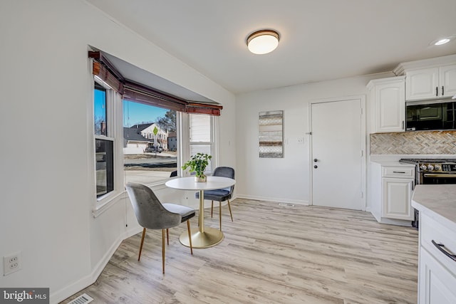 dining area featuring light wood finished floors, visible vents, and baseboards