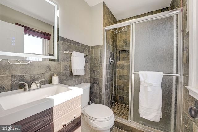 full bathroom with toilet, a stall shower, tile walls, and vanity