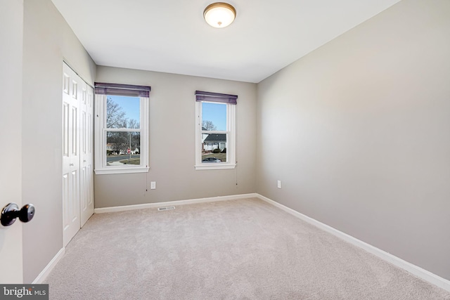 unfurnished room featuring baseboards, visible vents, and light colored carpet