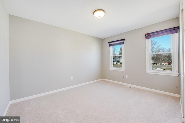 spare room with carpet floors, visible vents, and baseboards